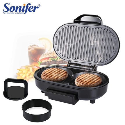 A black Sonifer electric grill with two round patties cooking inside, shown open on a white background with a lid insert and two small accessories in front. The Sonifer logo appears in the top left, and a blurred burger, fries, and drink is visible in the background as a usage context.