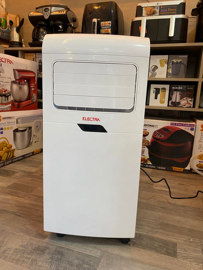 A white Electra portable air conditioner and heater standing on a gray wood floor in a retail store, with product boxes and other appliances visible in the background.