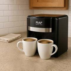 Black coffee machine with two white mugs filled with coffee on a kitchen counter.