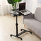 Adjustable laptop stand on wheels next to a gray sofa with a laptop on top