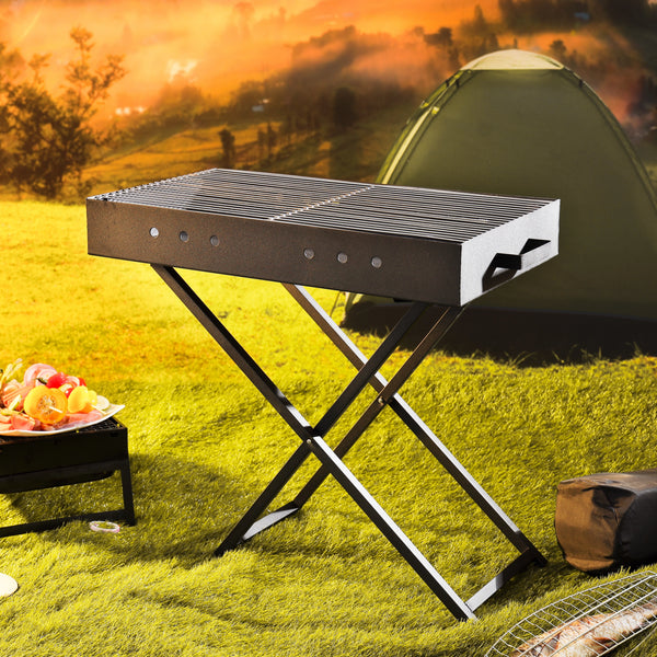 Portable grill on grass with a tent and scenic background