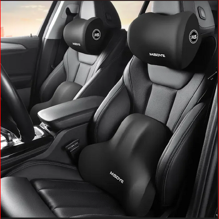 Car interior with black headrest and shoulder support pillows on gray seats.