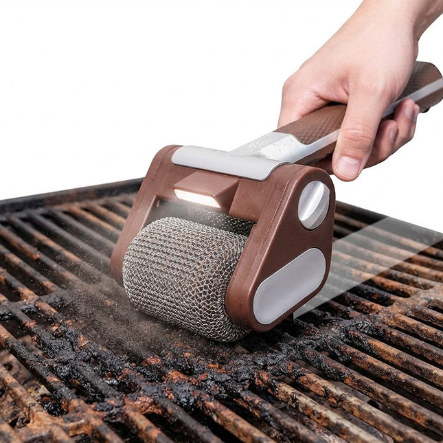 A hand holds a brown and silver grill cleaning roller brush with an integrated light, scrubbing a dirty grill grate over a white background.